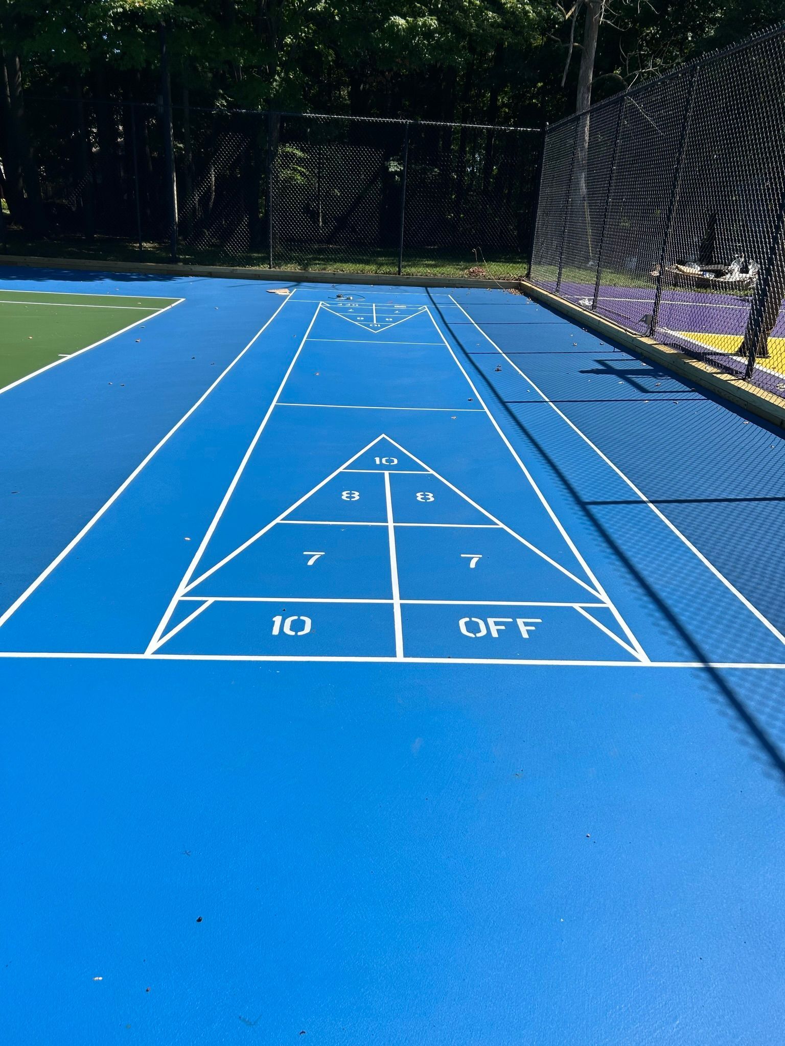A blue shuffleboard court with the letters n1 and off painted on it