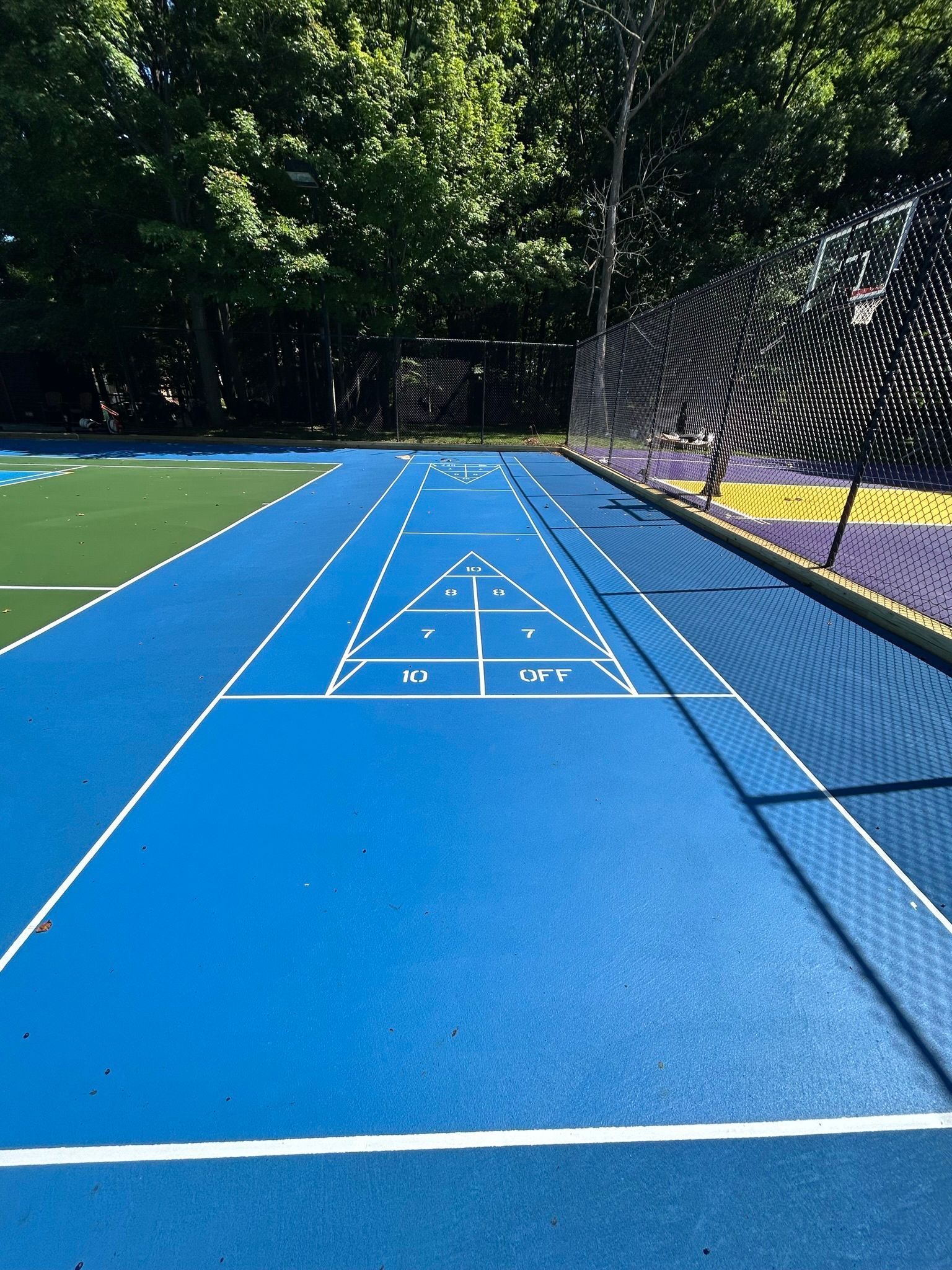 A blue tennis court with trees in the background