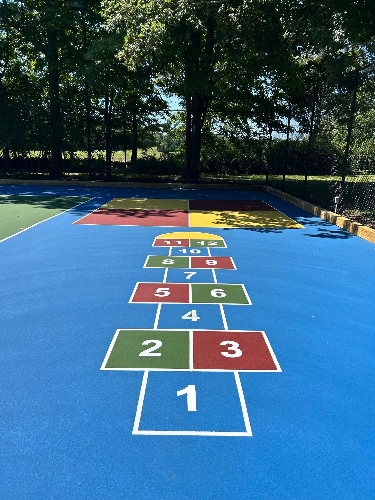 A blue playground with a hopscotch pattern painted on it.