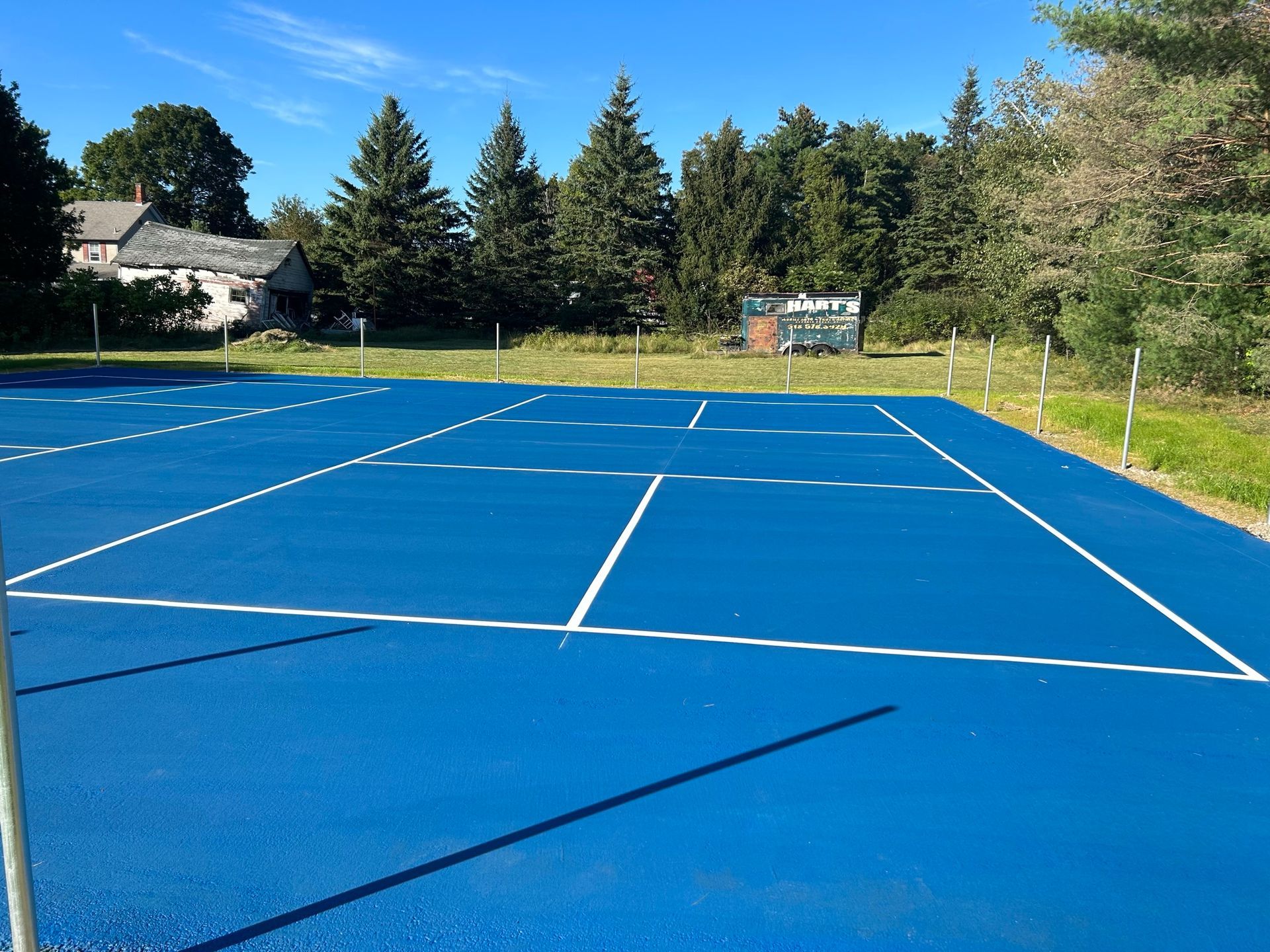 A blue tennis court with trees in the background