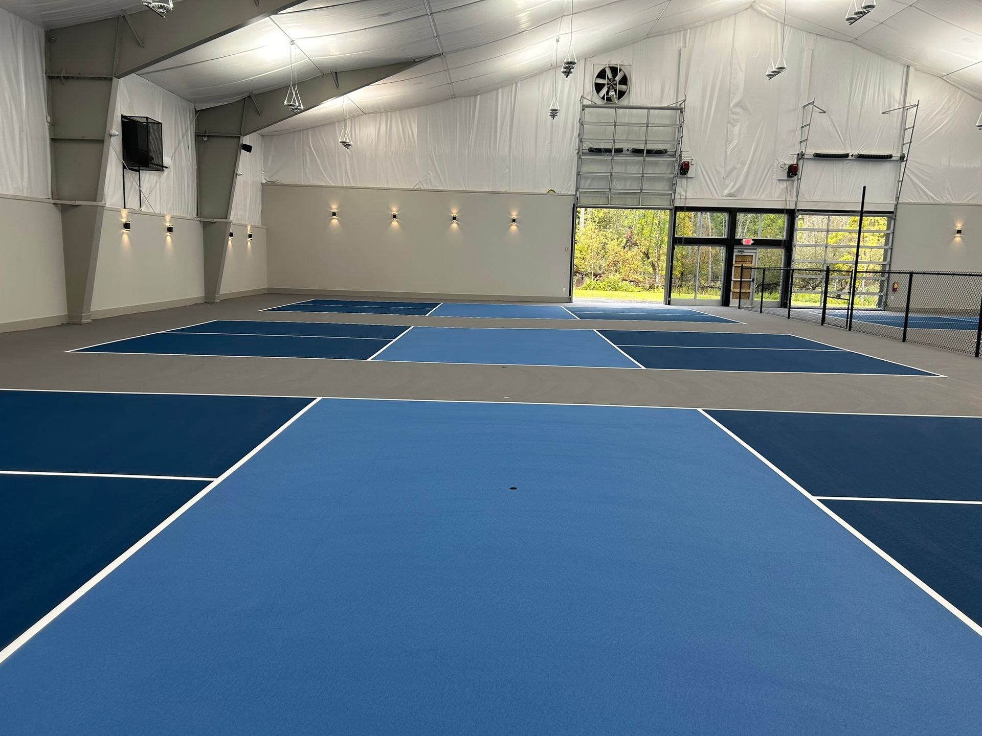 A large indoor tennis court with blue and white tennis courts.