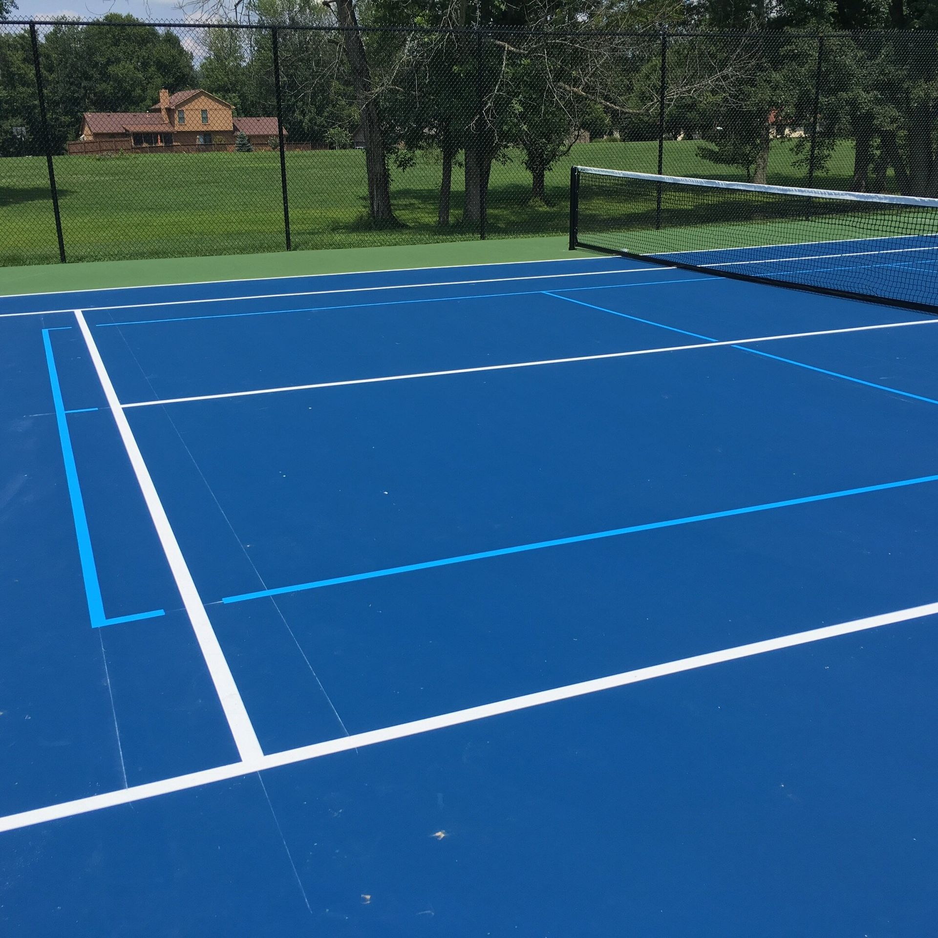 A blue tennis court with white lines and a net