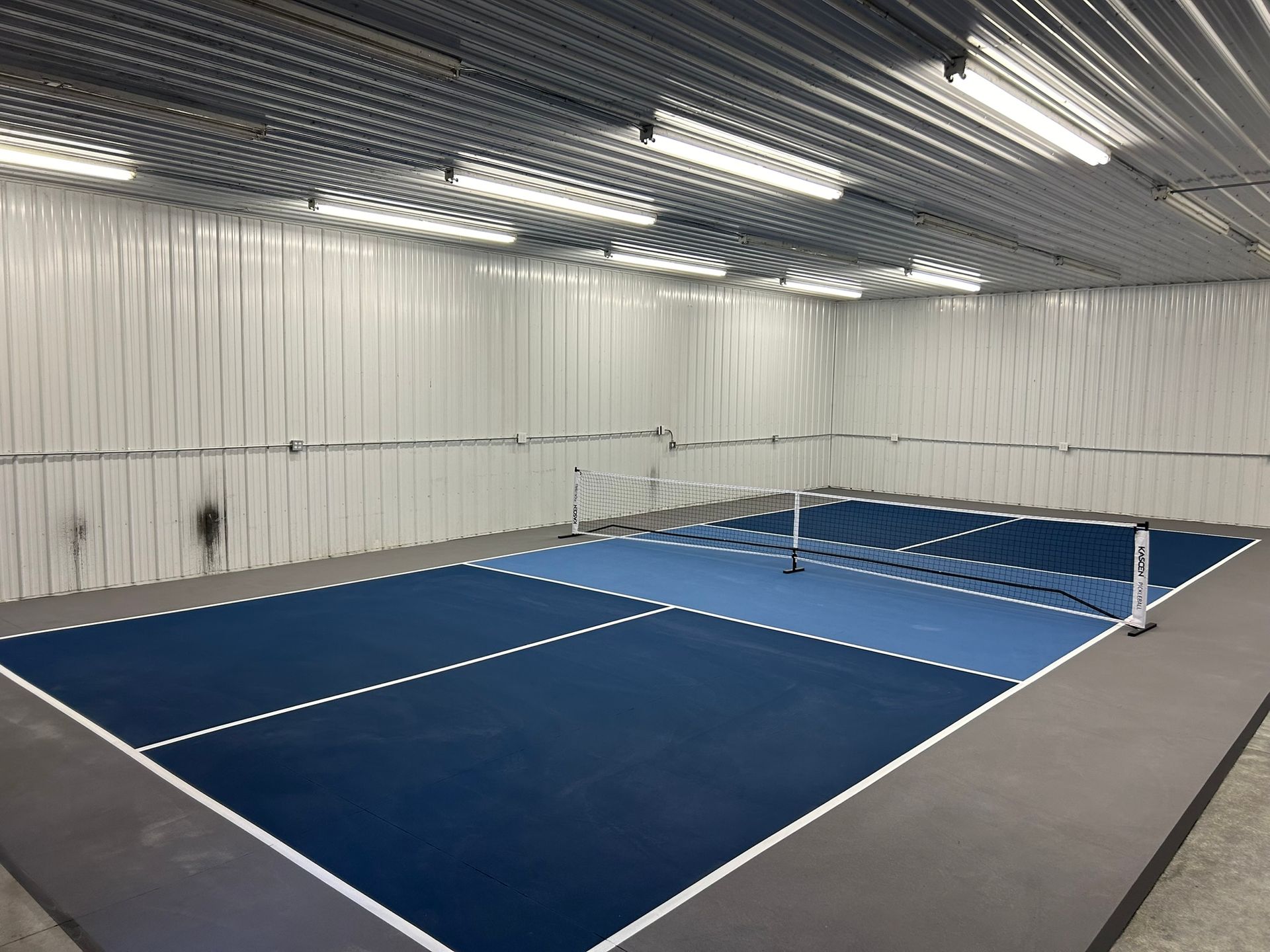 An indoor tennis court with blue and white lines
