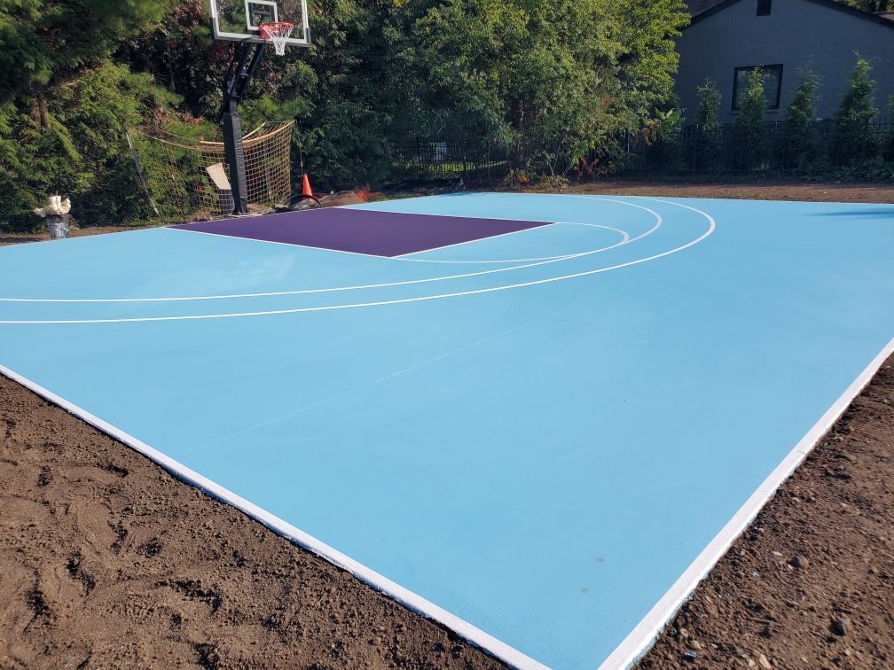 A blue and purple basketball court with a basketball hoop in the background.