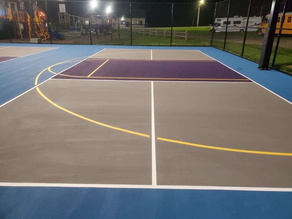 A basketball court with a fence around it at night.
