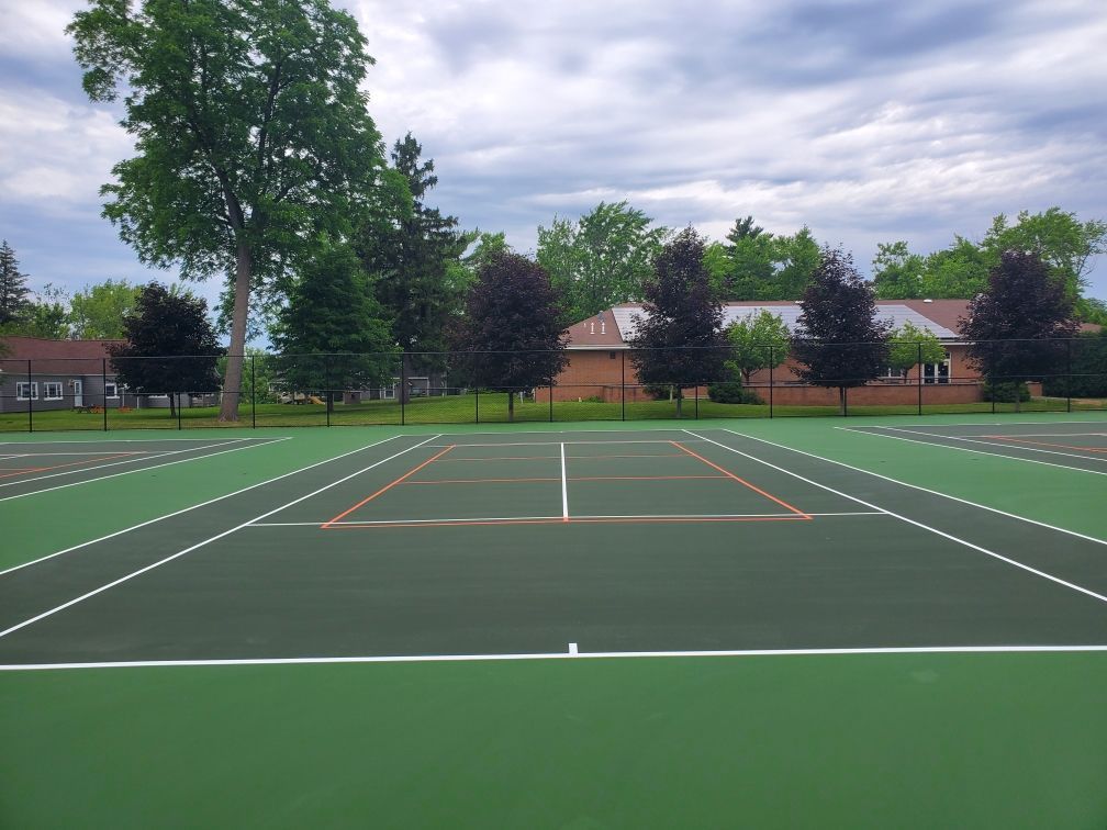 A tennis court with a house in the background