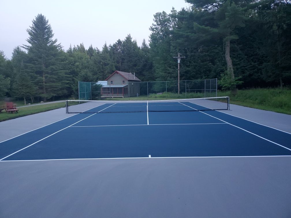 A tennis court with a house in the background