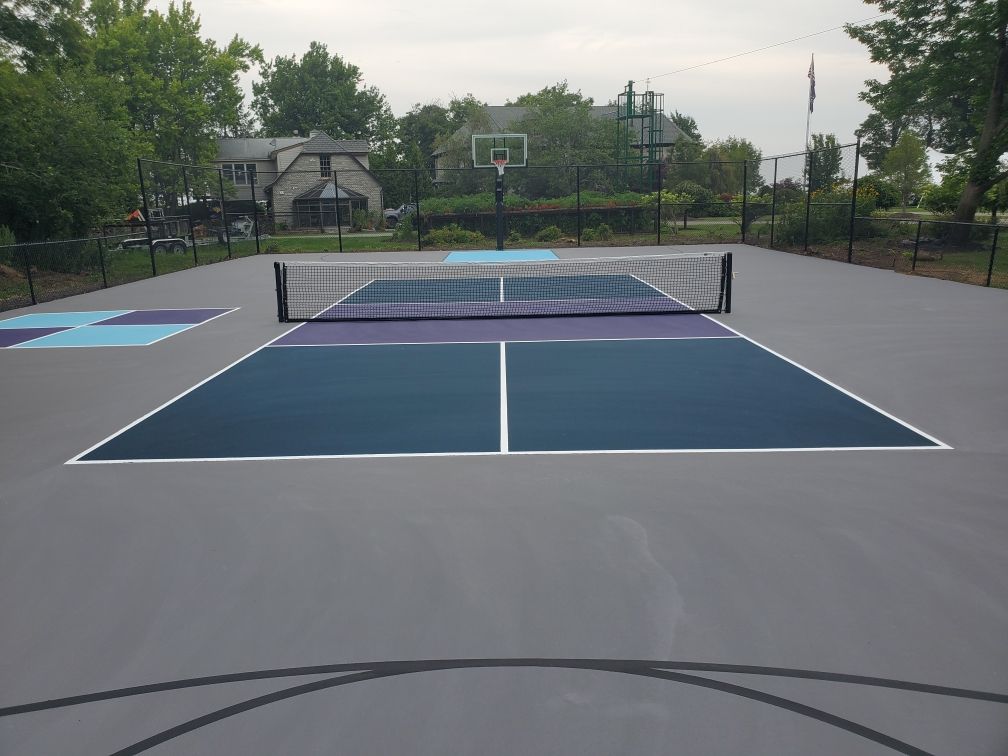 A tennis court with a basketball hoop in the background