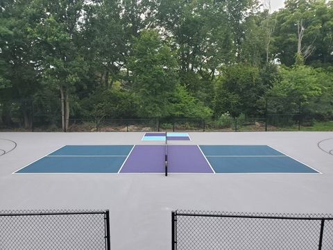 A blue and purple tennis court with trees in the background