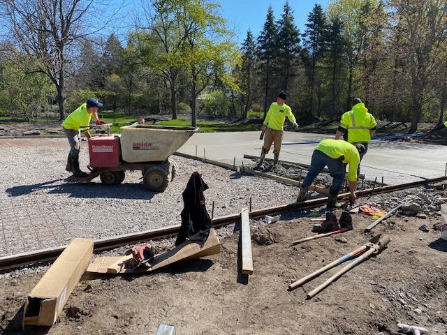 A group of construction workers are working on a concrete driveway.