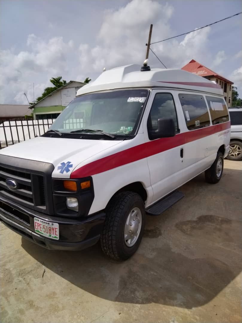 A white ambulance with a red stripe on the side is parked in a parking lot