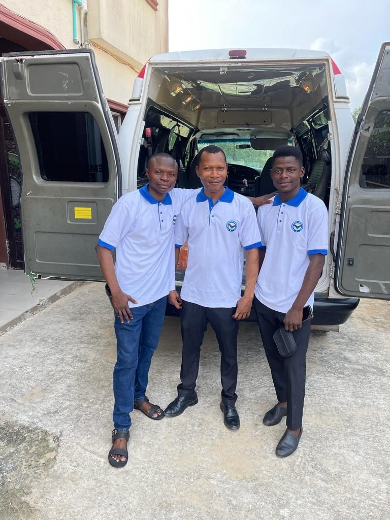 Three men are posing for a picture in front of a van.