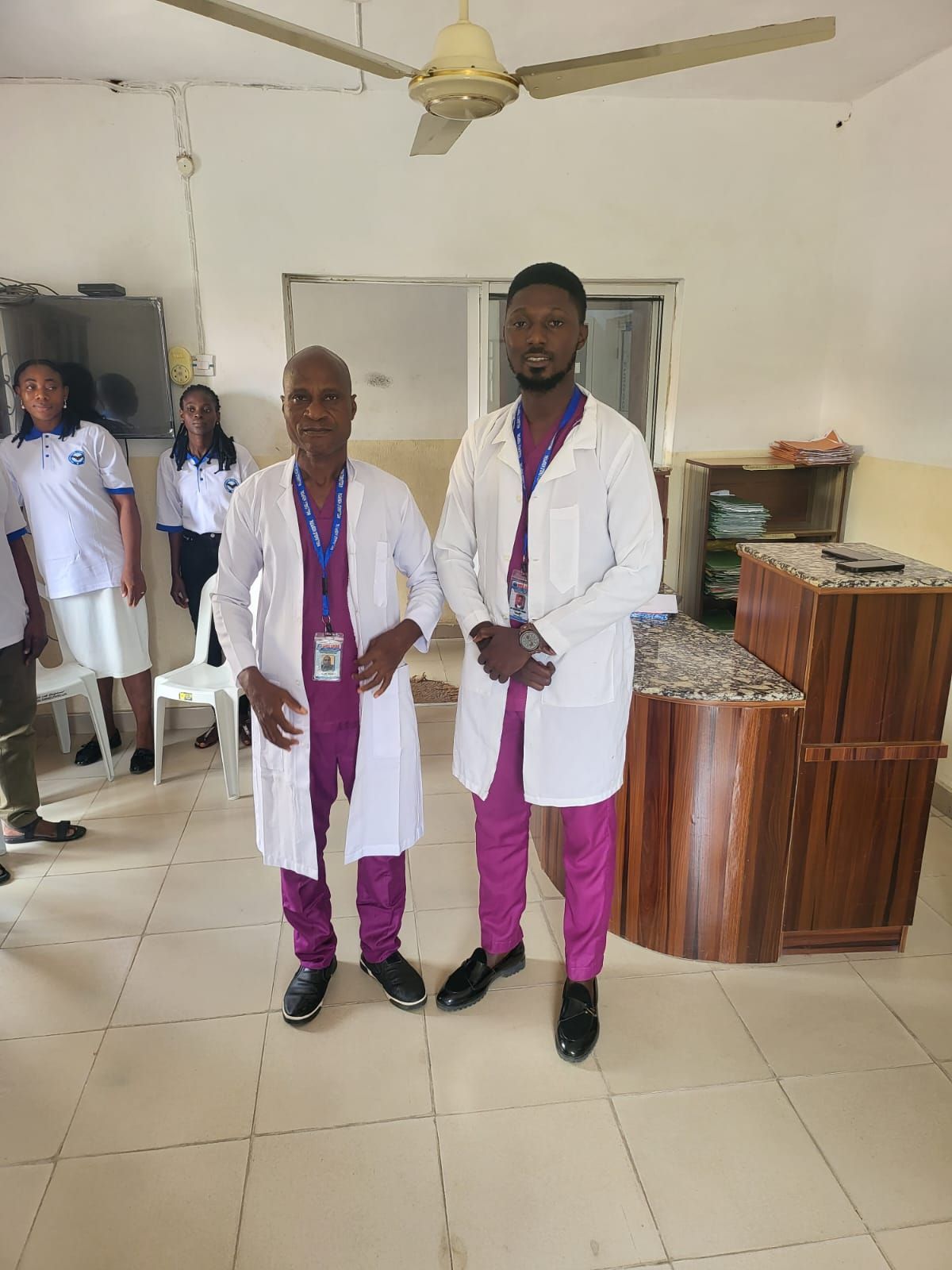 Two men in lab coats are standing next to each other in a room.