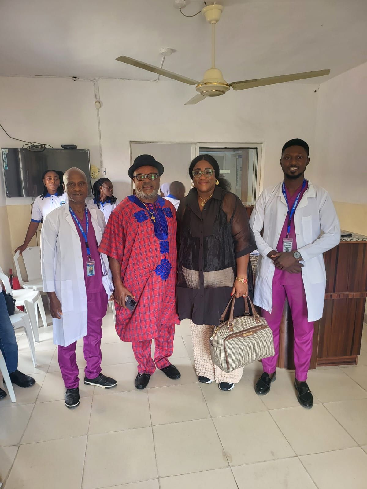 A group of people are posing for a picture in a room with a ceiling fan.