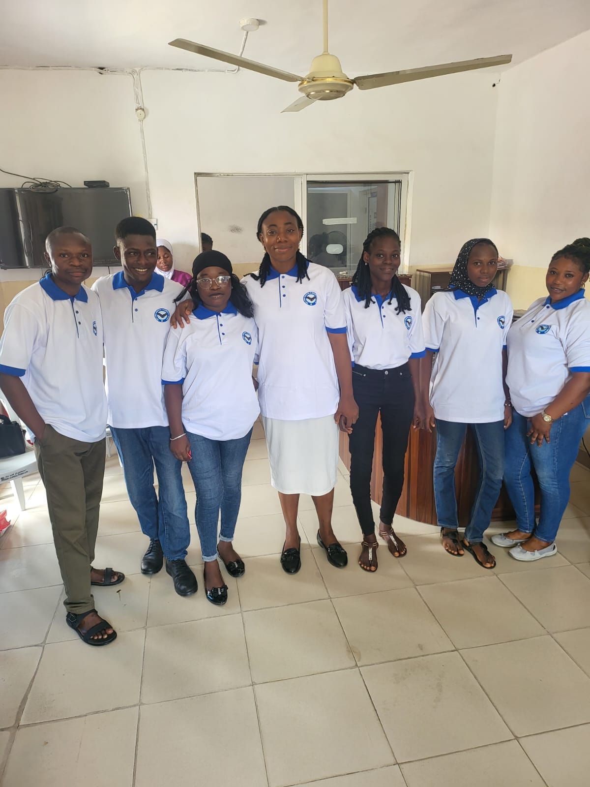 A group of people are posing for a picture in a room with a ceiling fan.