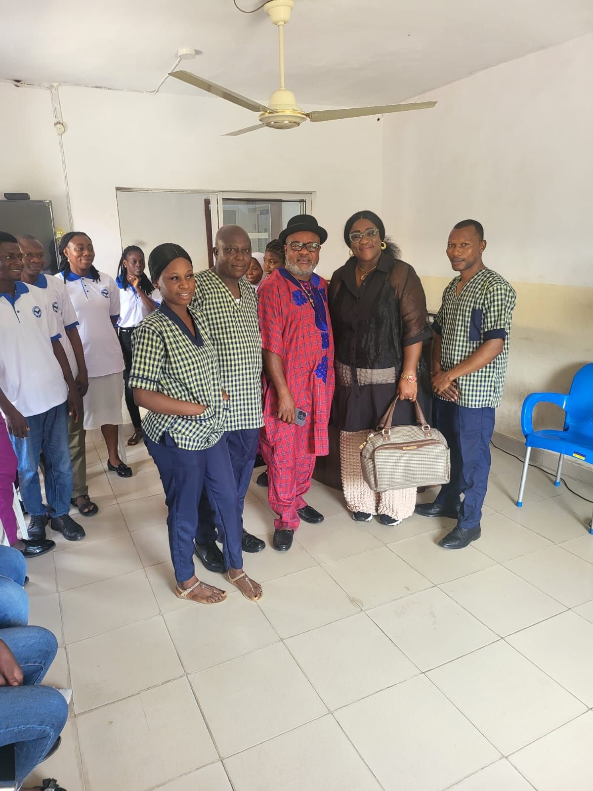 A group of people are posing for a picture in a room with a ceiling fan.