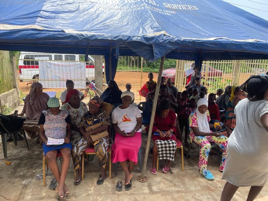A group of people are sitting under a blue tent.