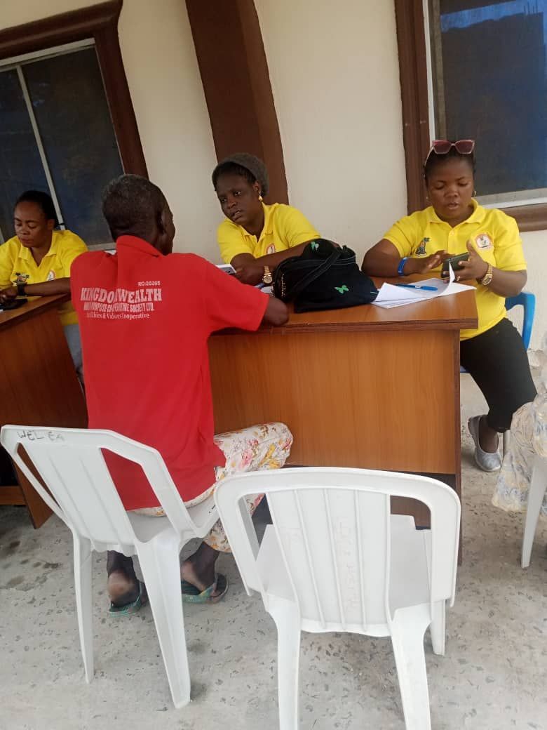 A man in a red shirt with the word peace on the back sits at a desk