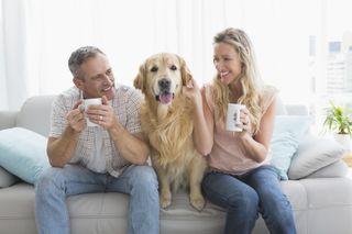 couple on couch with dog while drinking from mug