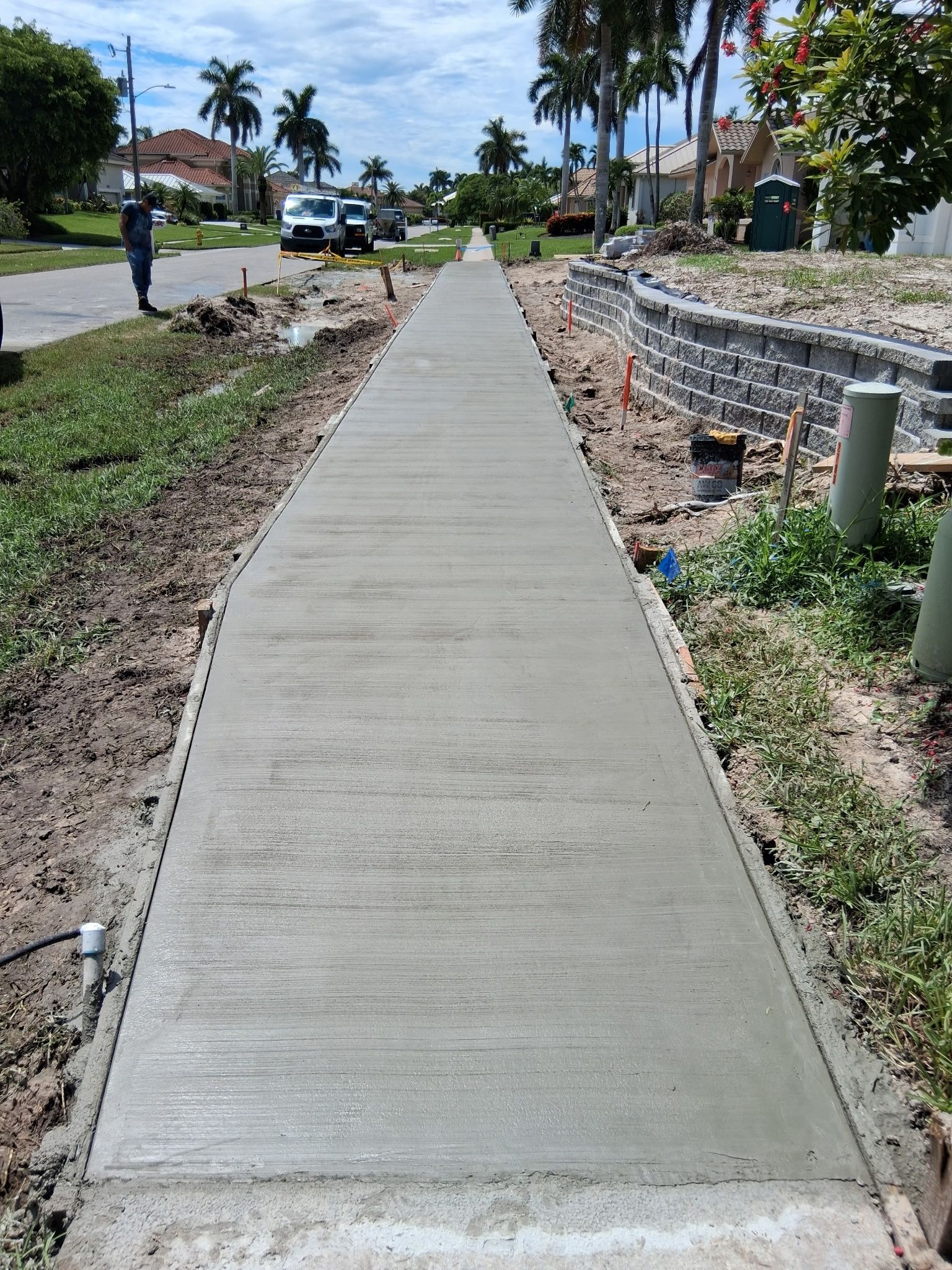 Newly poured concrete sidewalk with a person standing nearby.