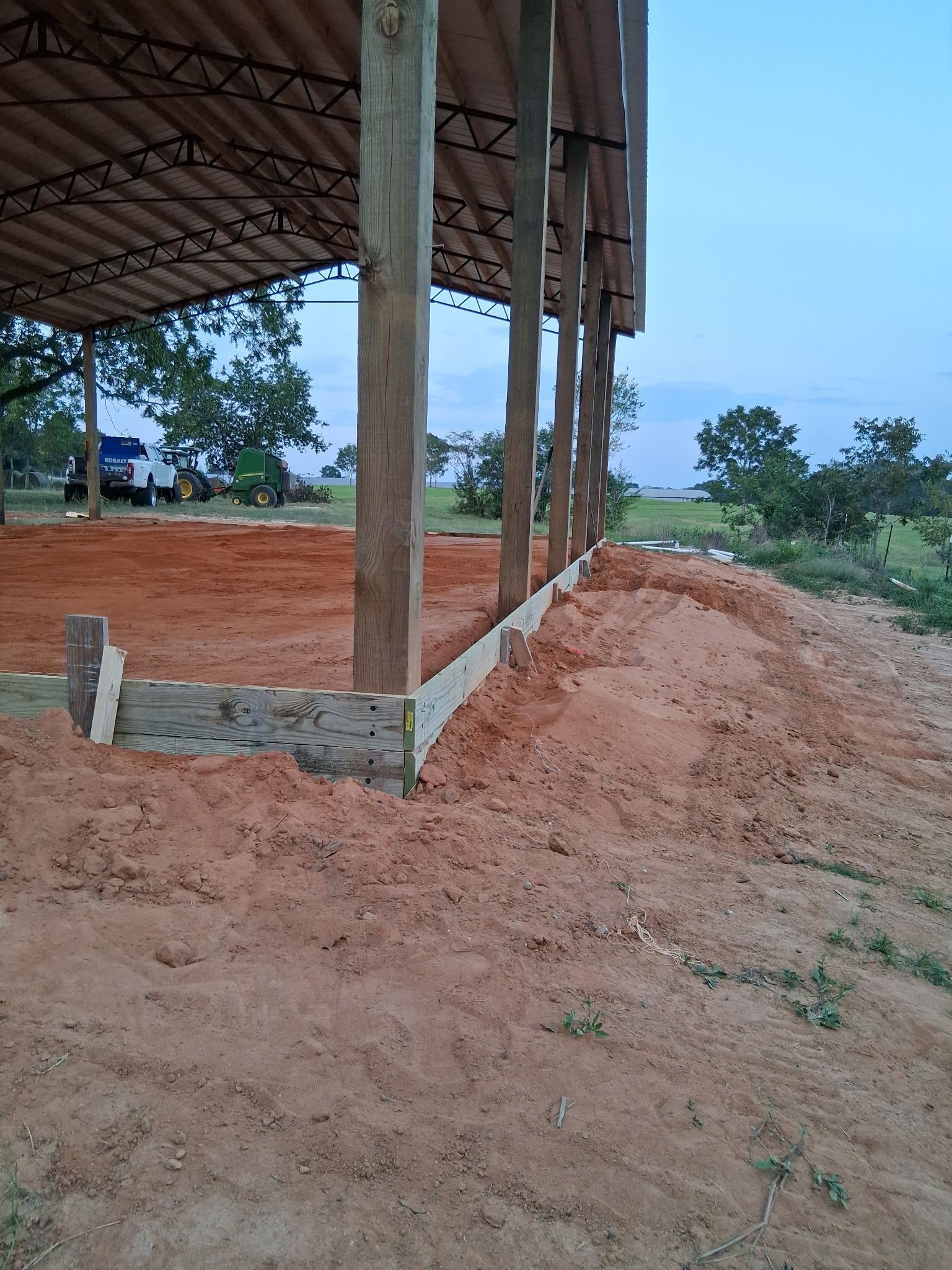 Construction site: Wooden posts supporting a roof; dirt ground, wooden border.