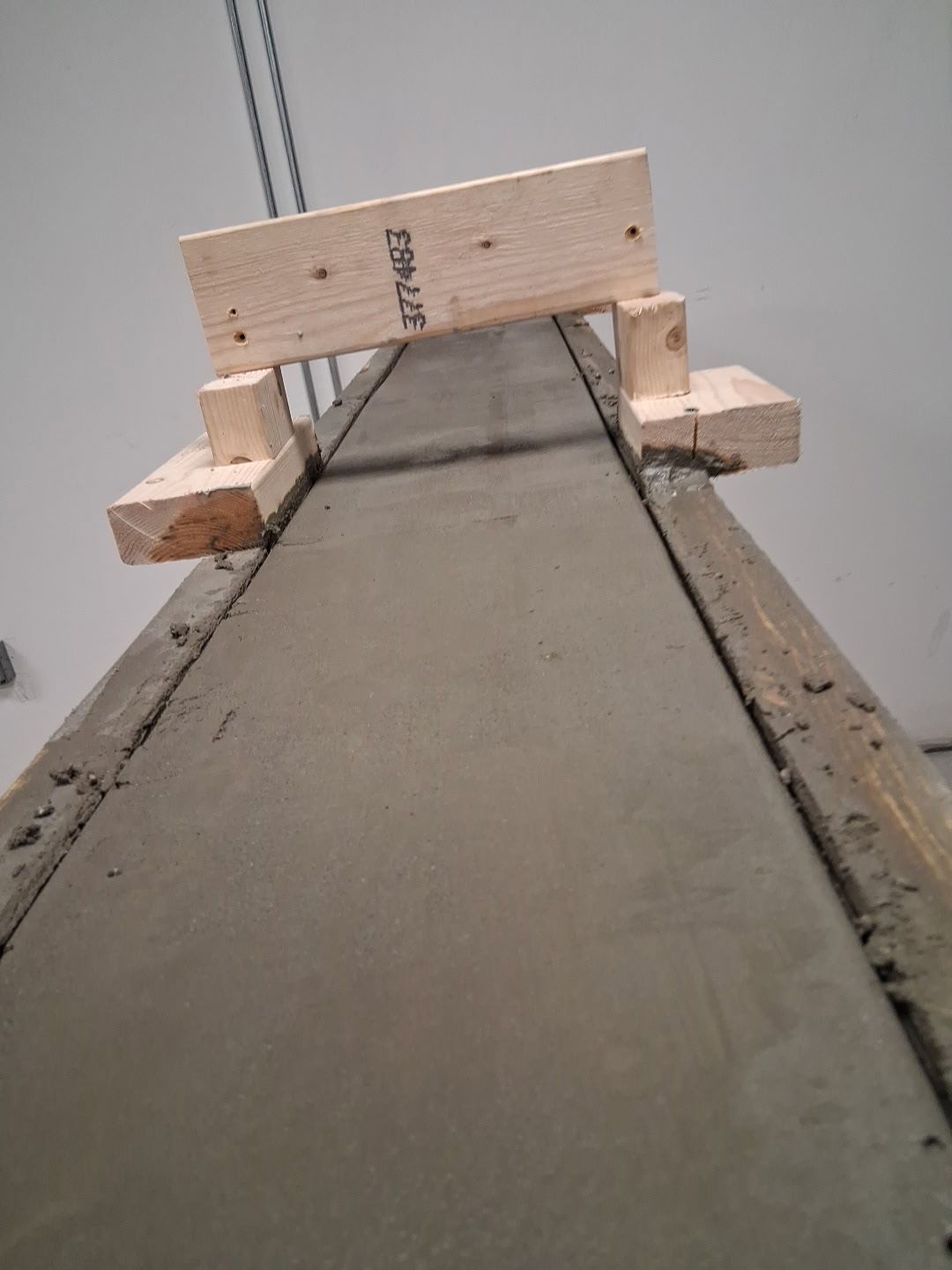Freshly poured concrete in a wooden form with wood supports.