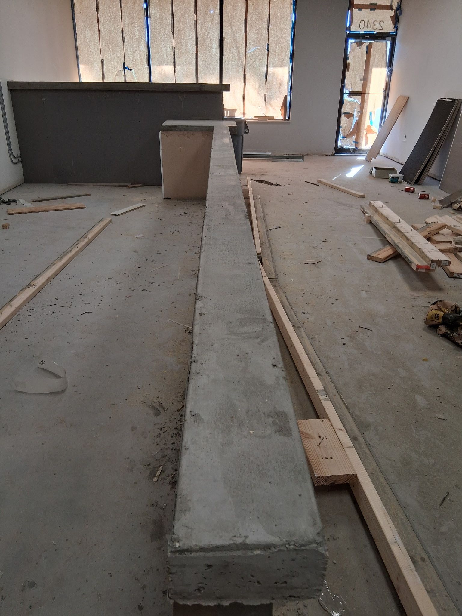 Concrete beam in room under construction; wooden beams and tools visible.
