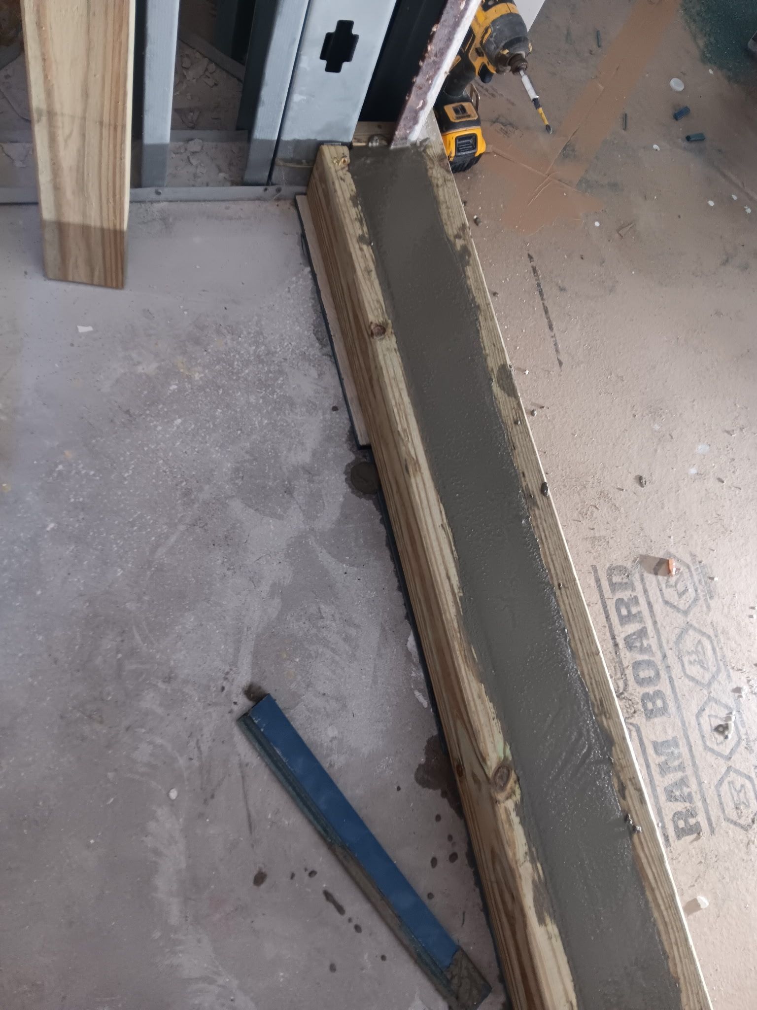 Concrete poured into wooden form on a floor, construction in progress.