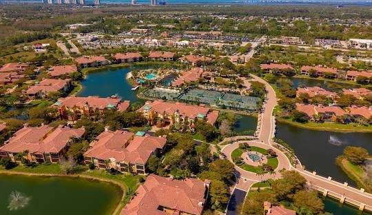 A sunset over a lake with trees in the foreground and a bridge in the background.