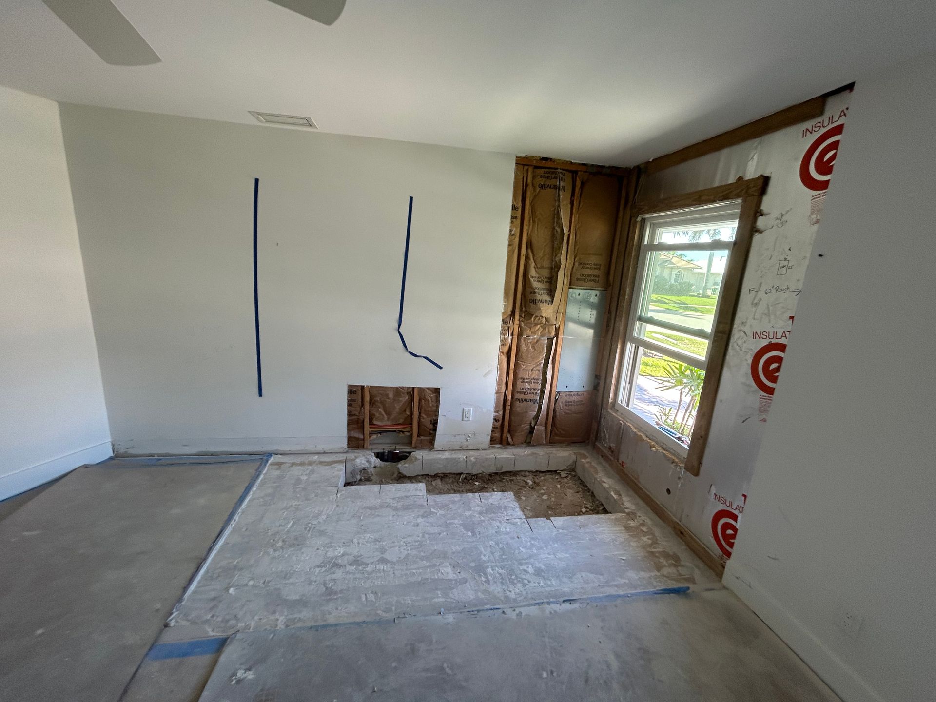 Room under renovation with exposed wall studs and window. Floor partially removed.