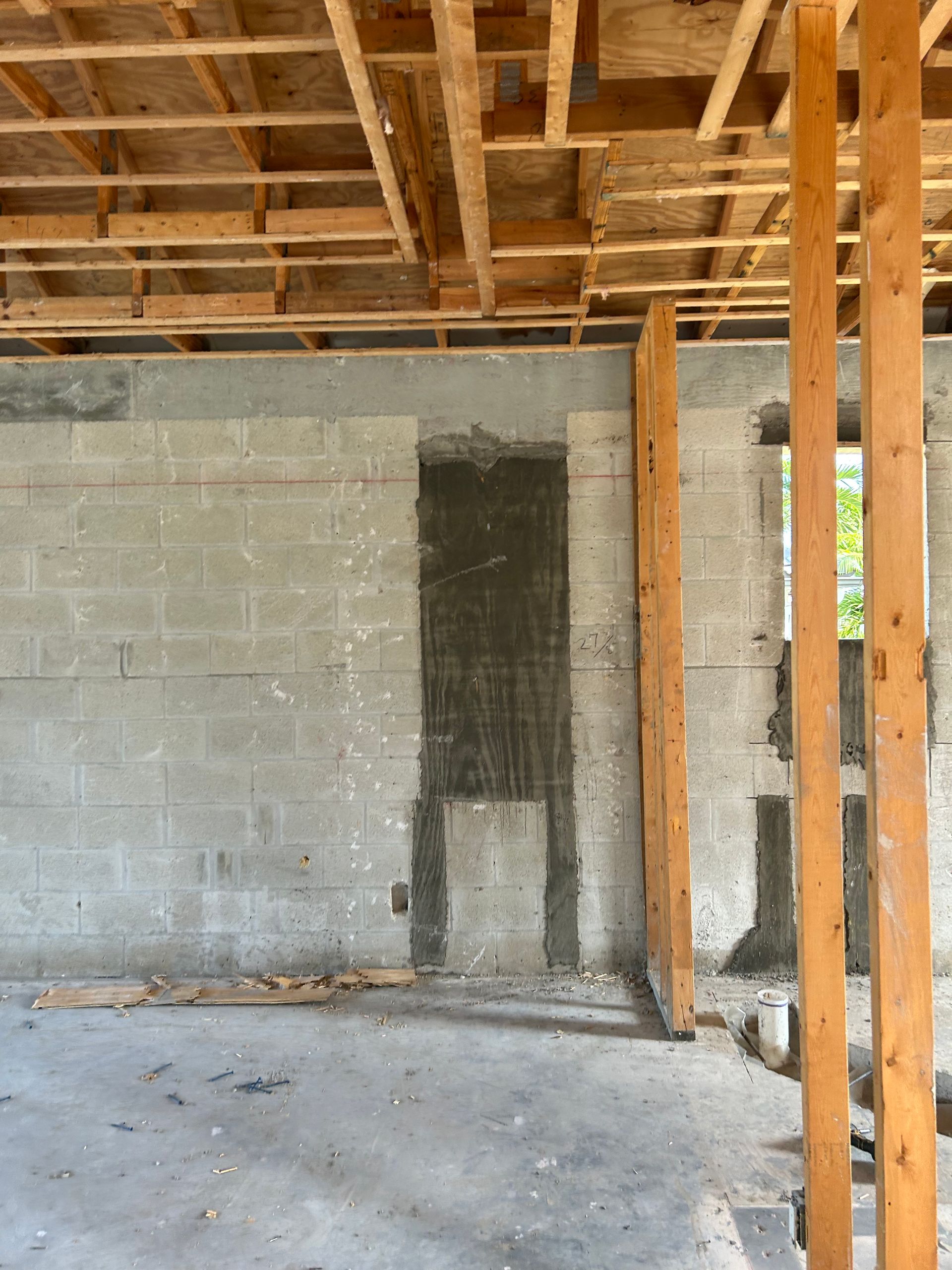 Construction site interior with exposed concrete block wall, wooden beams and framing.