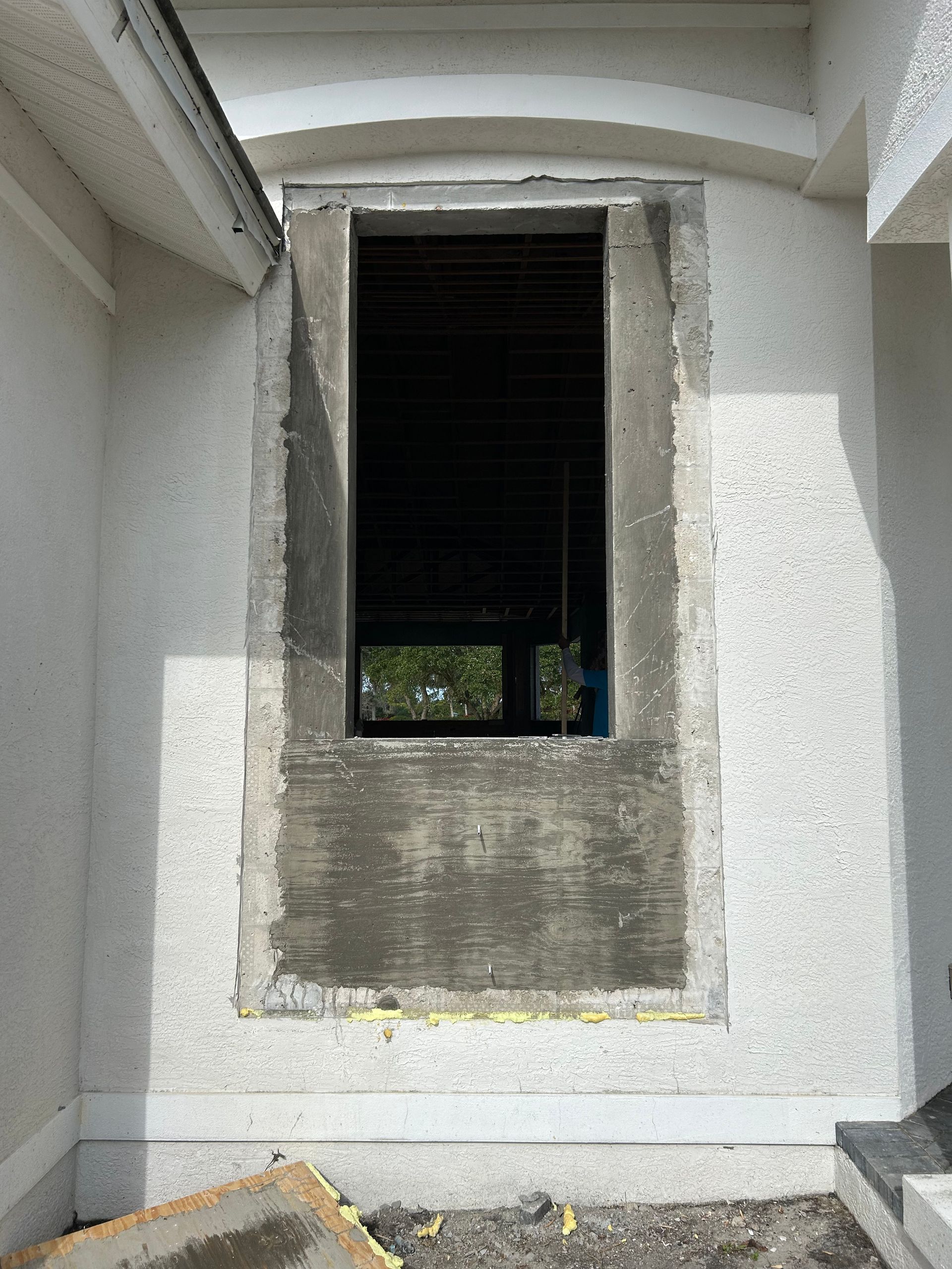 Empty rectangular window opening in a stucco wall, with concrete frame.