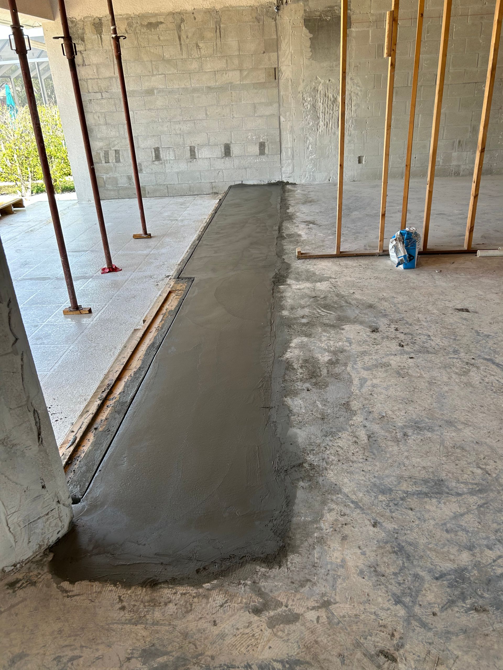 Concrete strip poured on a construction site, with wooden forms and supports visible.