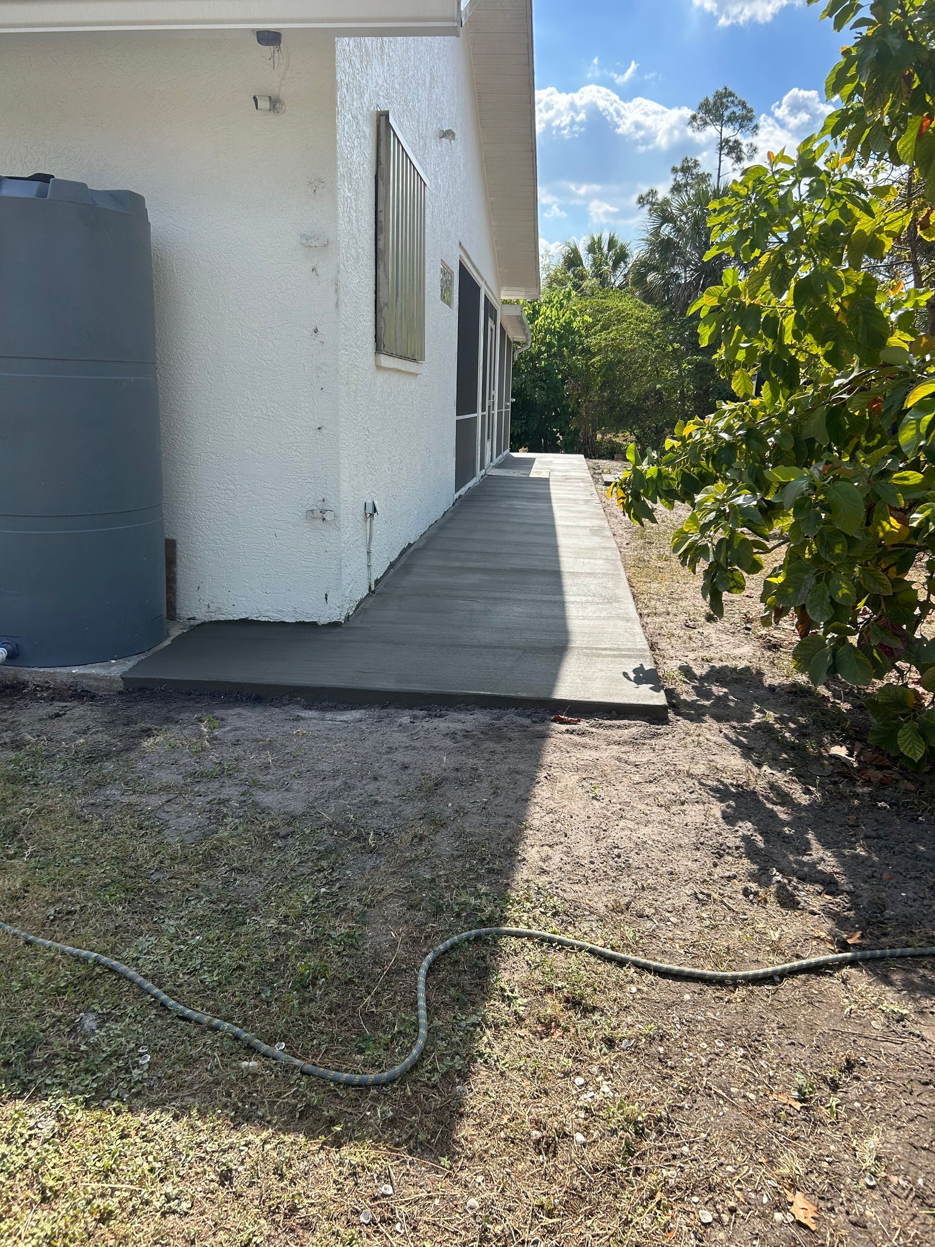 A concrete ramp slopes up to a white building. A water tank is left of the ramp.