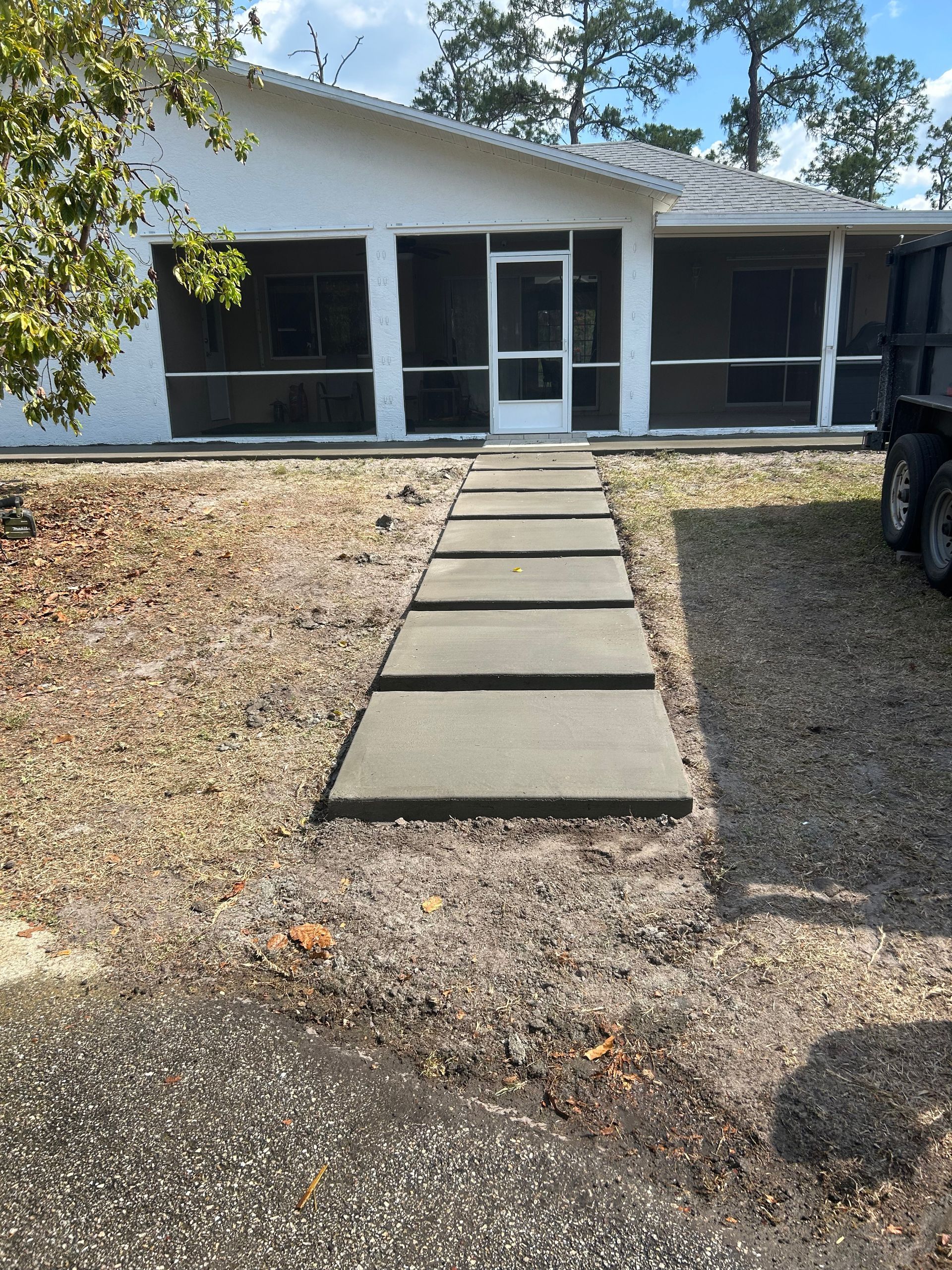 A person is working on the sidewalk in front of a house.