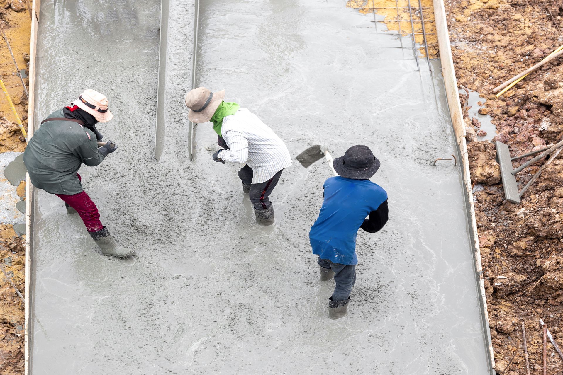 A group of men are working on a concrete driveway.