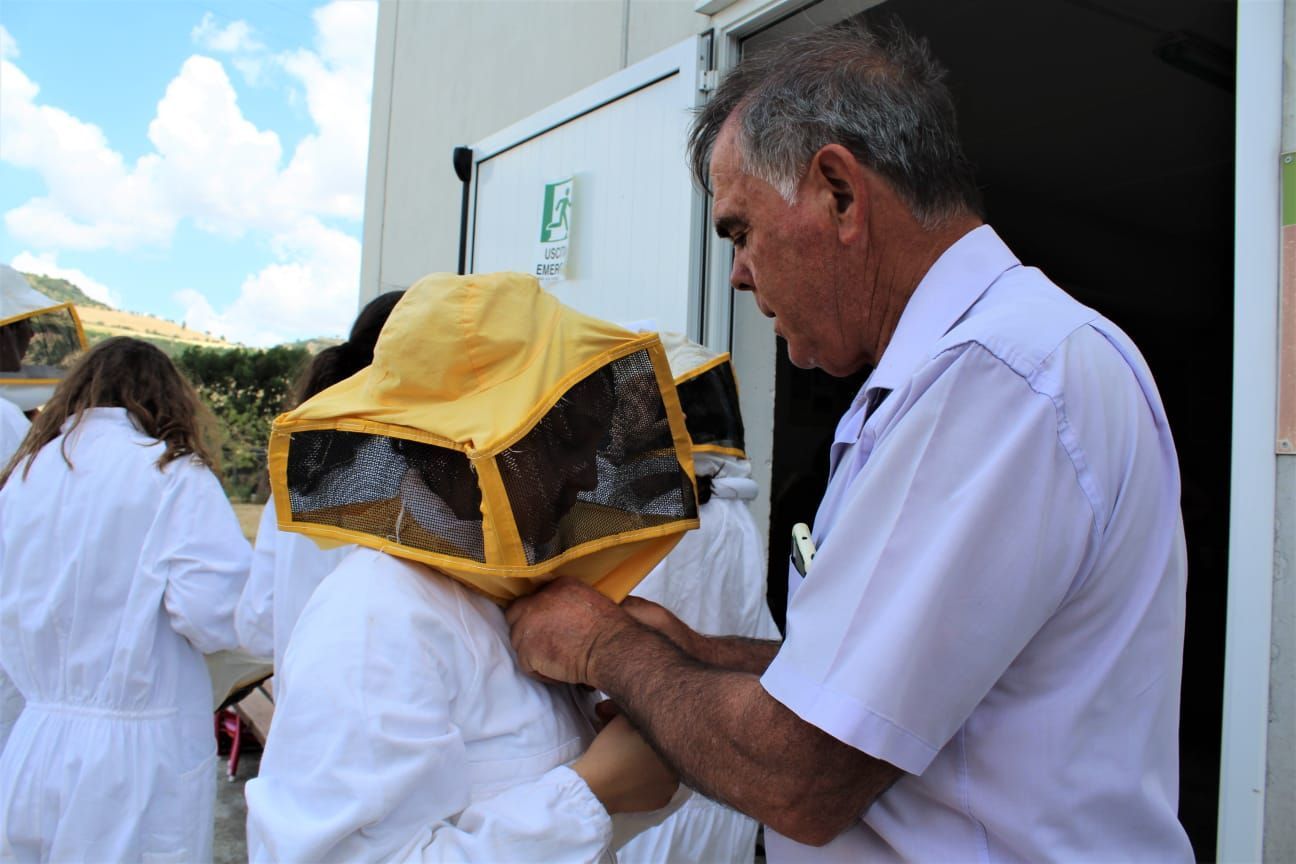 Un uomo aiuta una donna a indossare il cappello dell'apicoltore.