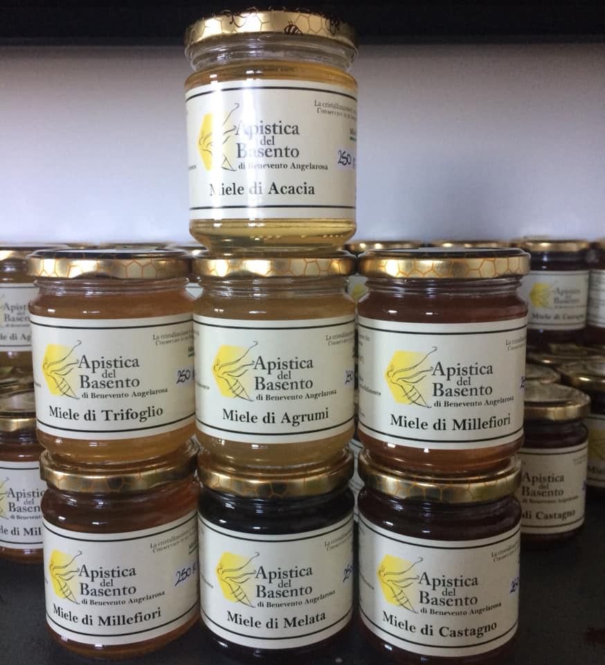 Una persona sta immergendo un mestolo per il miele in un barattolo di miele.