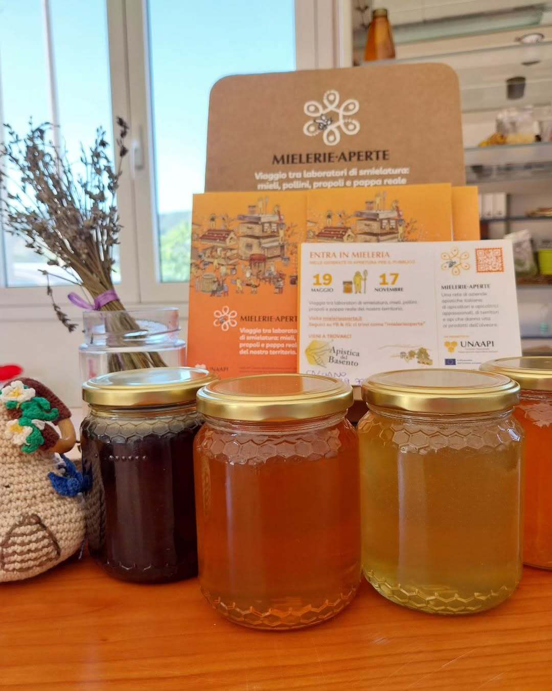 Tre barattoli di miele sono appoggiati su un tavolo di legno.