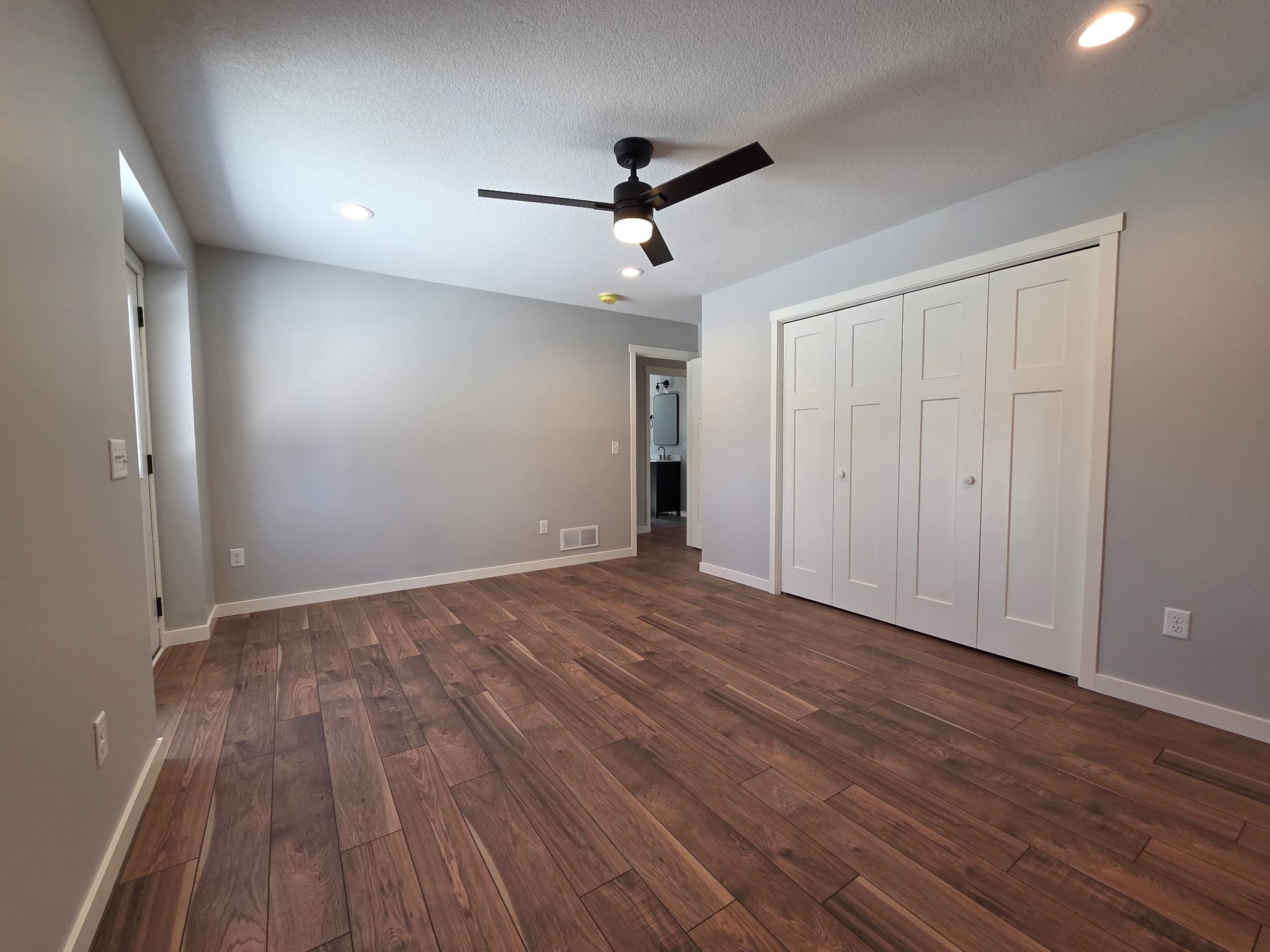 Yellow house with a two-car garage, lush green lawn, and blue sky with clouds.