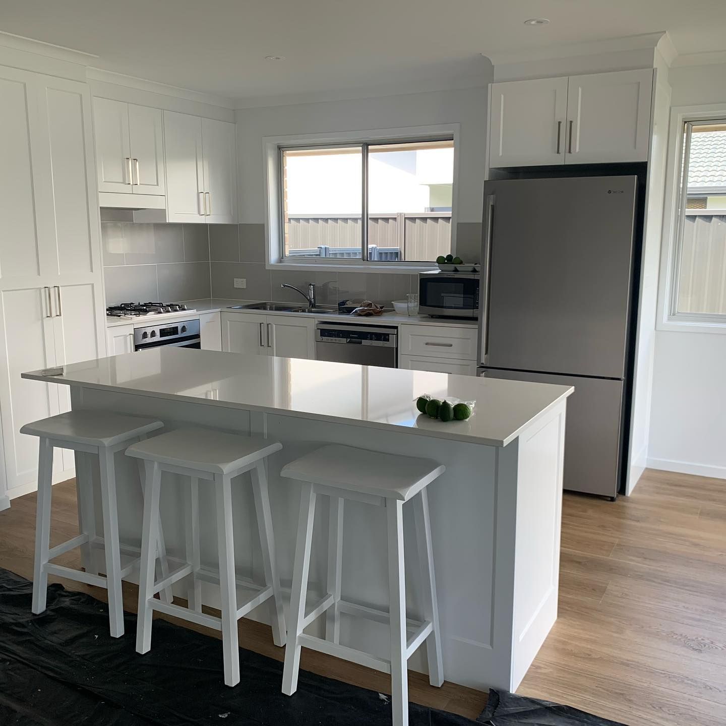 A Kitchen With White Cabinets , Stools , A Refrigerator And A Stove — D & L Custom Cabinets  In Kingscliff, NSW 