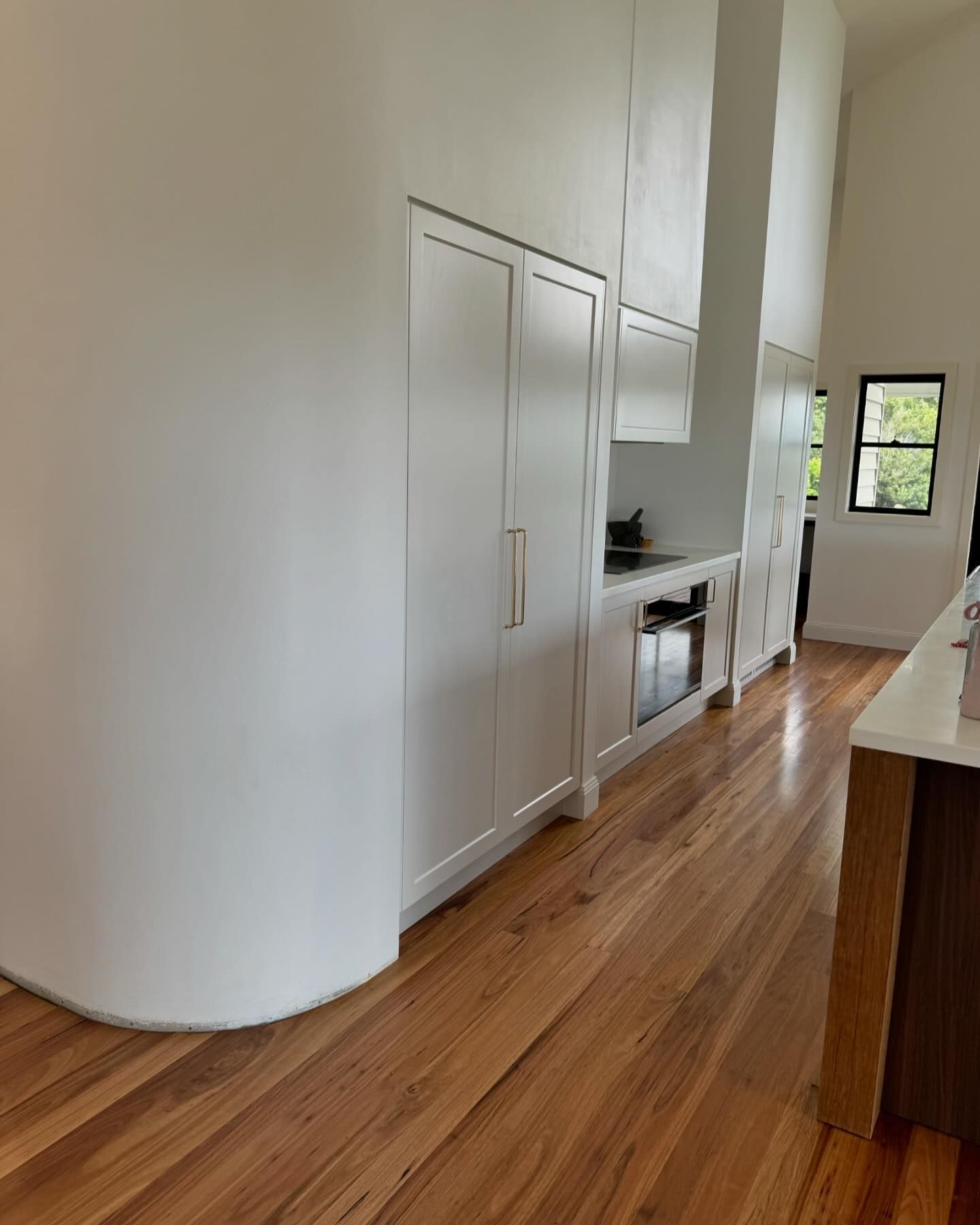 A Kitchen With Hardwood Floors And White Cabinets — D & L Custom Cabinets  In South Murwillumbah, NSW 