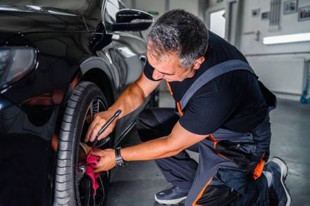 A man is changing a tire on a car in a garage.