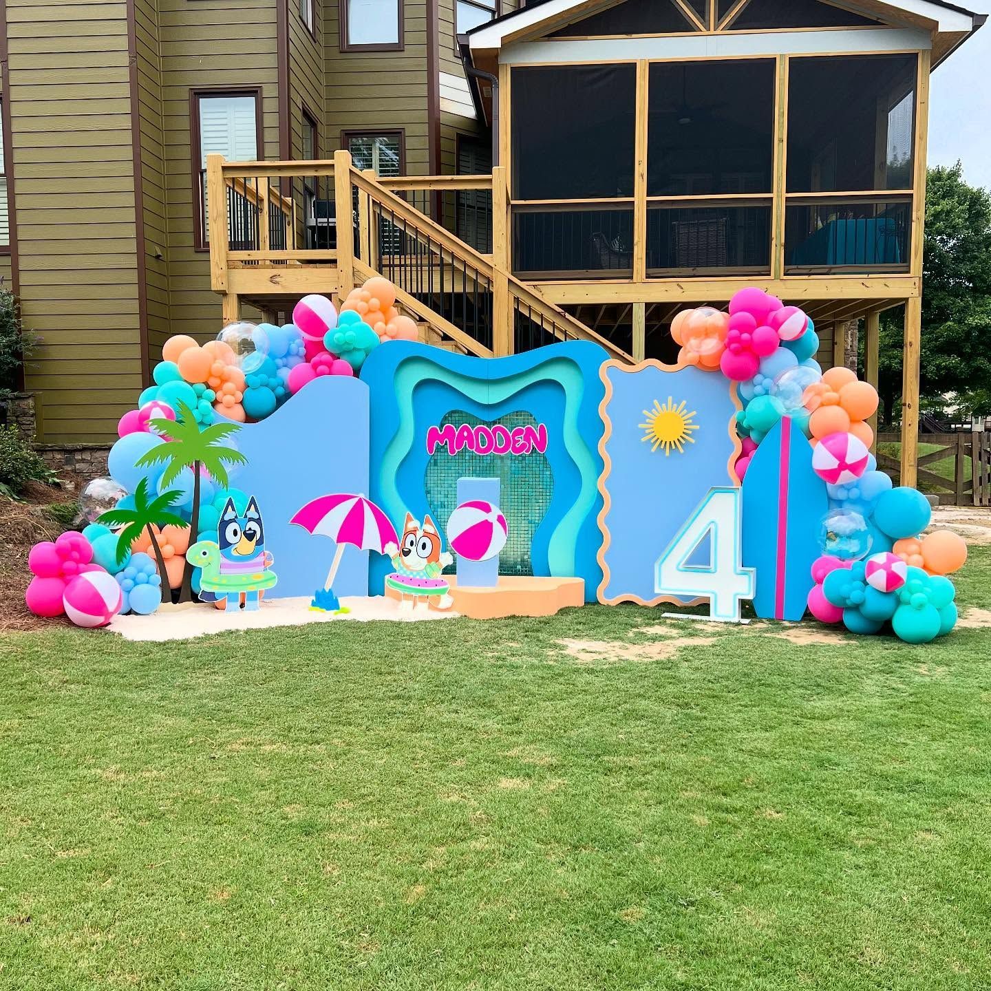 Bluey-themed beach party backdrop with balloons, characters, and a 