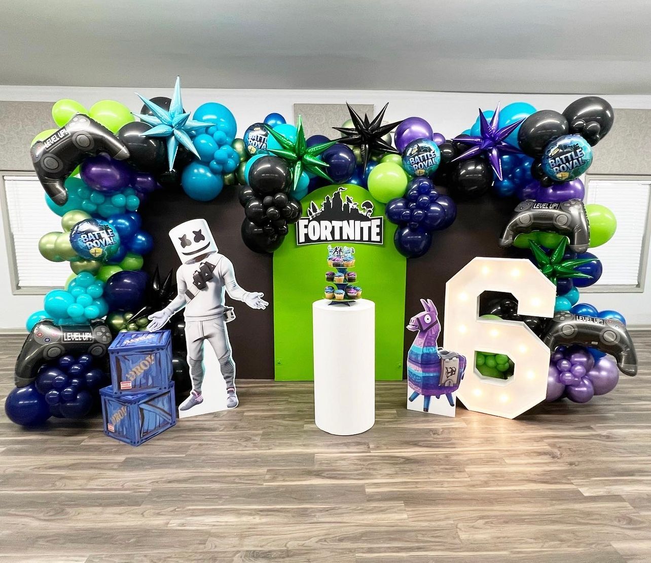 Fortnite-themed party decorations with balloons, cardboard cutouts, and a light-up 