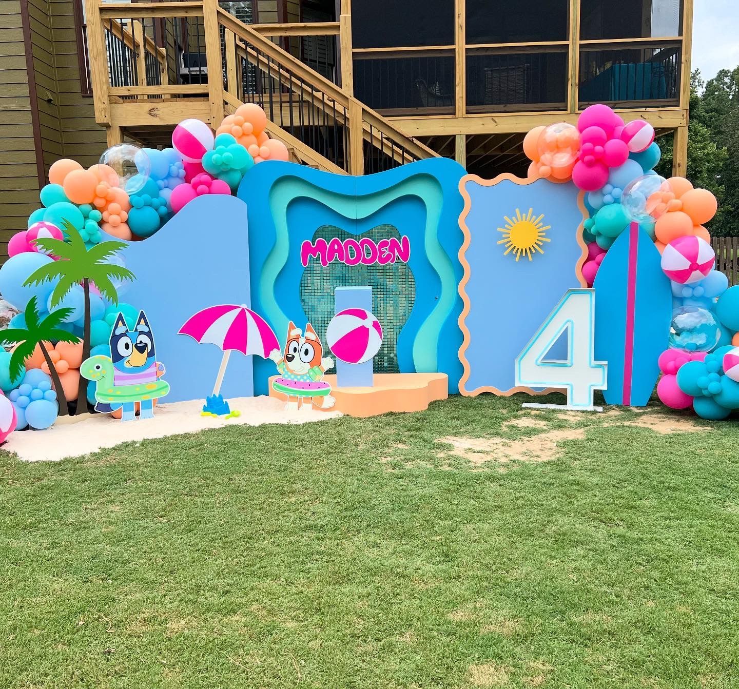 Bluey-themed 4th birthday party backdrop with balloons, cutouts, and beach theme.
