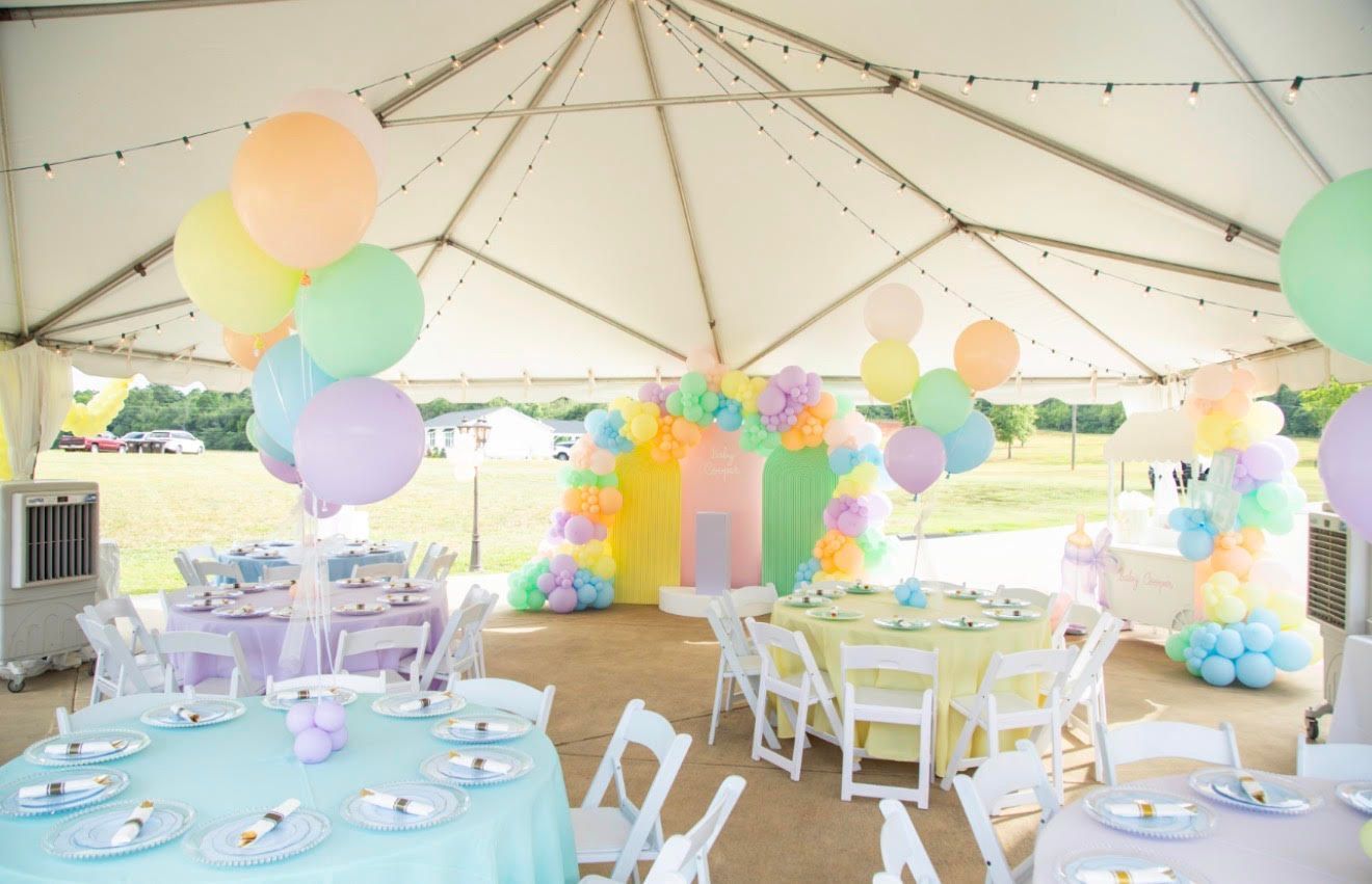 Party tent interior with pastel balloons, tables, and decorations.