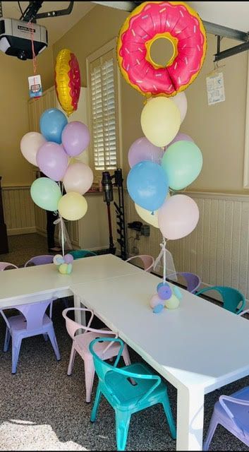 Party setup with tables, chairs, and balloon decorations including donut-shaped balloons.