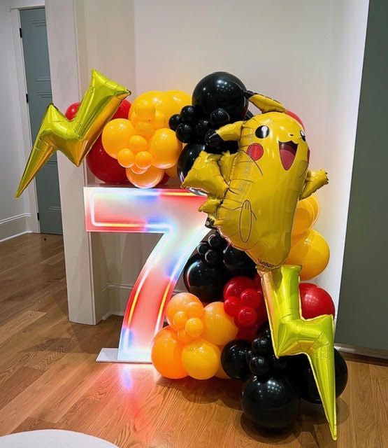A Pikachu-themed balloon display with the number 7, lightning bolts, and colorful balloons.