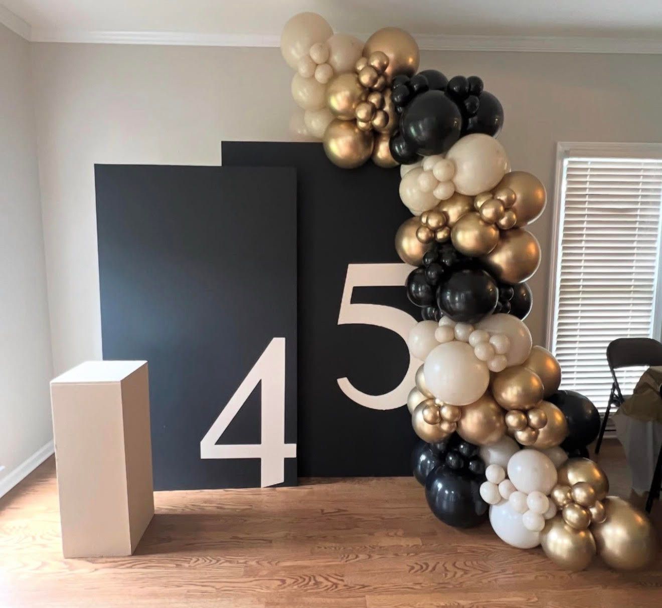 Black, gold, and white balloon arch with number cutouts of 